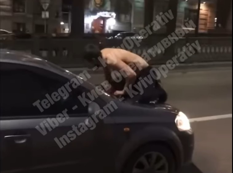 В центре Киева парень с оголенным торсом ехал на капоте легковушки (ВИДЕО)